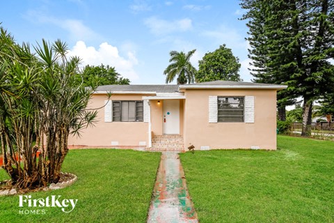 a home with a green lawn and a palm tree