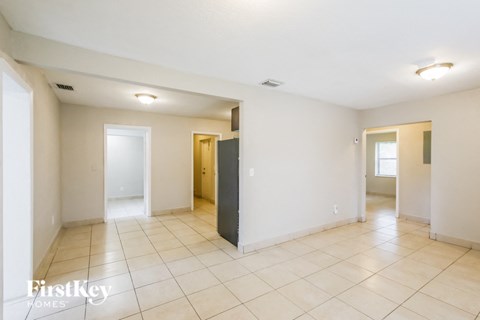 a spacious living room with tiled flooring and white walls