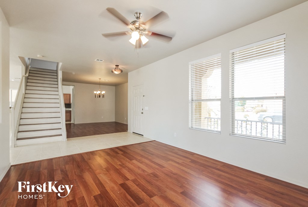 an empty living room with a staircase and a ceiling fan