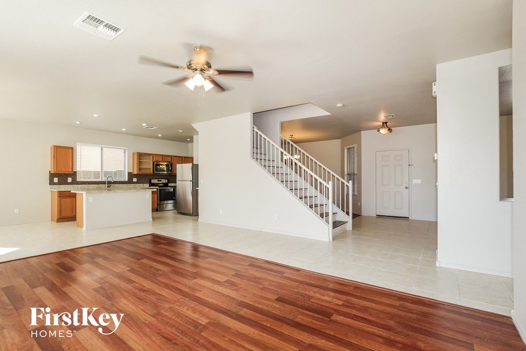 an empty living room with a ceiling fan and a staircase