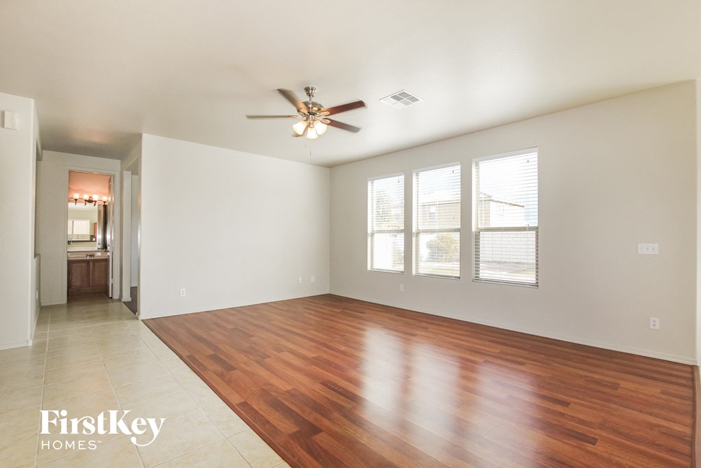 an empty living room with wood floors and a ceiling fan
