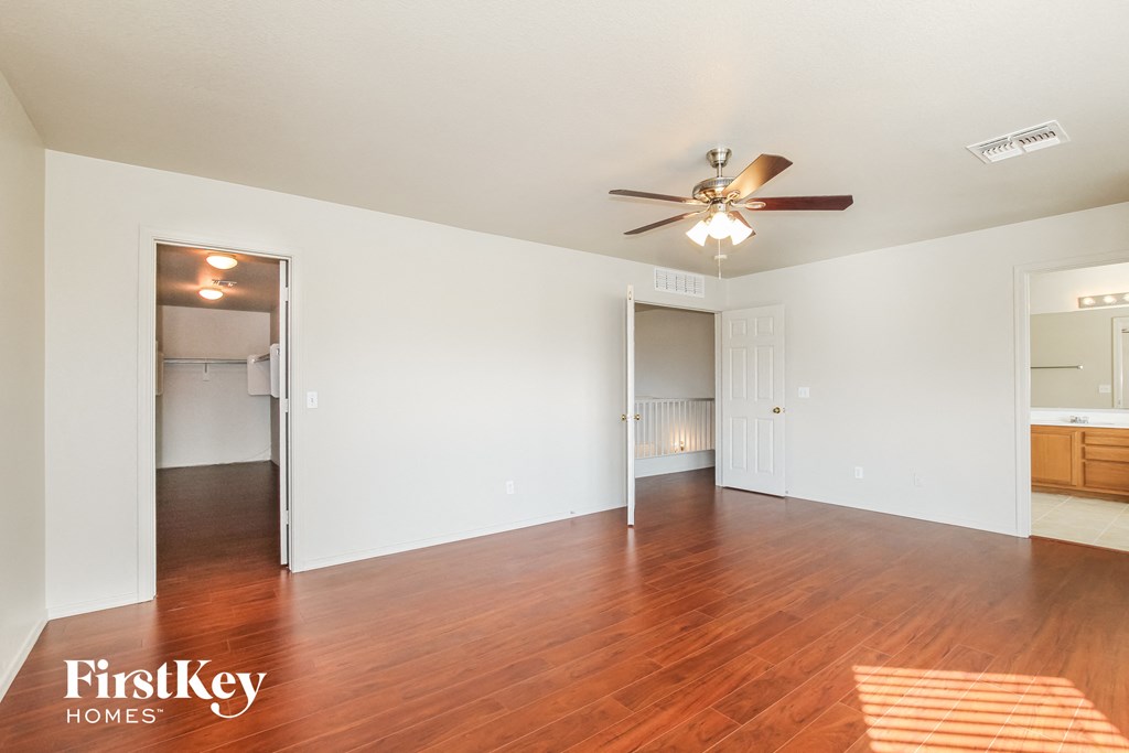 an empty living room with wood flooring and a ceiling fan