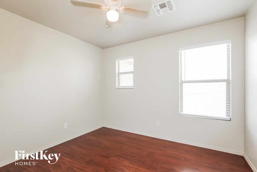 a bedroom with wood flooring and a ceiling fan