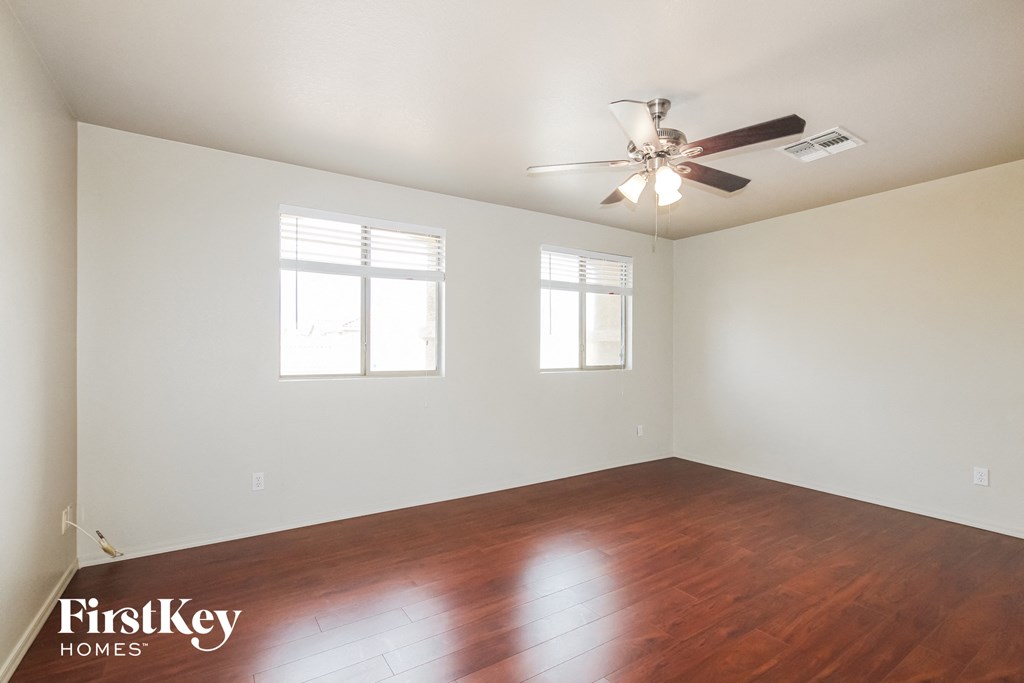 the living room with wood floors and a ceiling fan