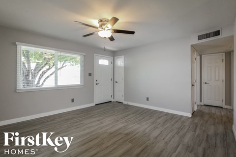 an empty living room with a ceiling fan and a window