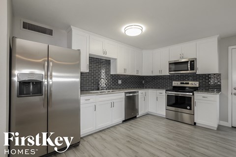 a white kitchen with stainless steel appliances and white cabinets