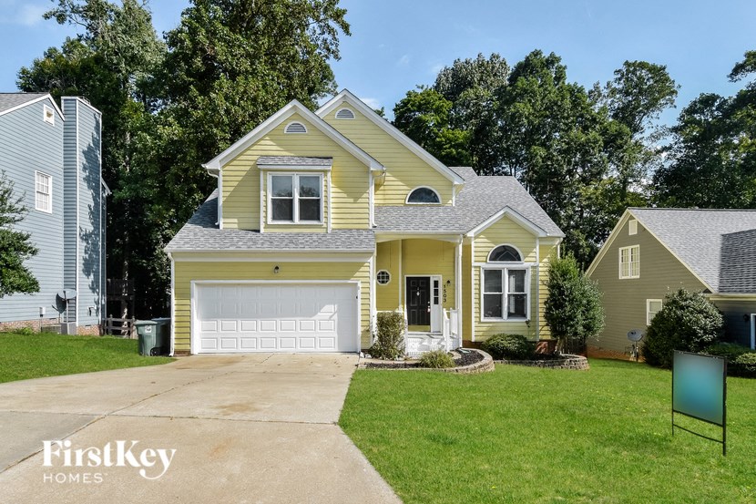 A yellow house with a garage door is for sale.