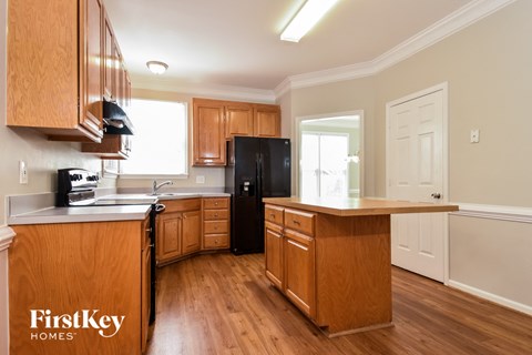 A kitchen with wooden cabinets and a black fridge.