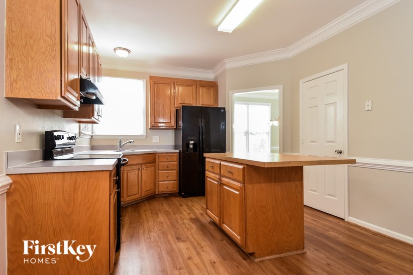 A kitchen with wooden cabinets and a black refrigerator.