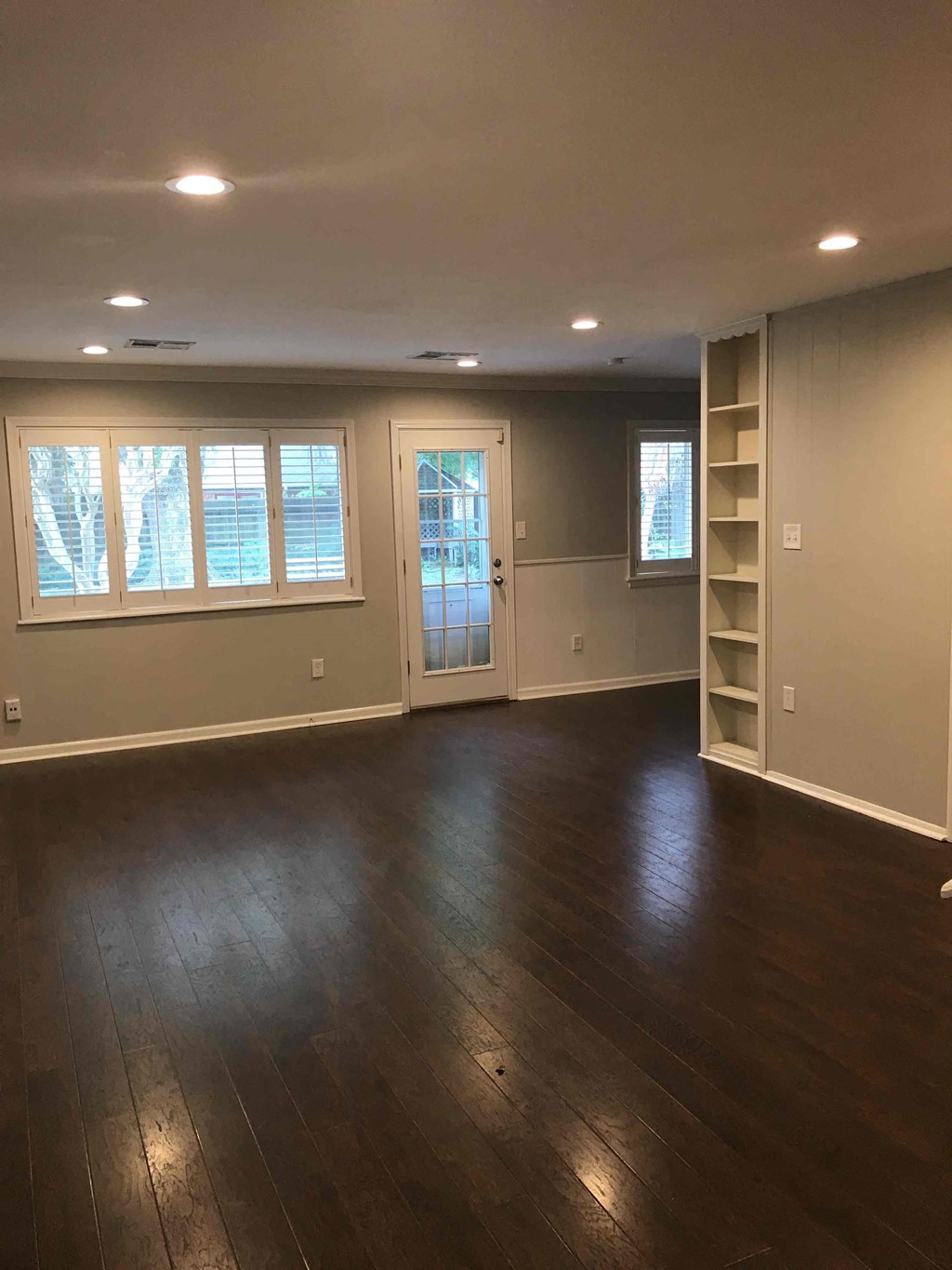 A room with wooden floors and a door leading to another room.