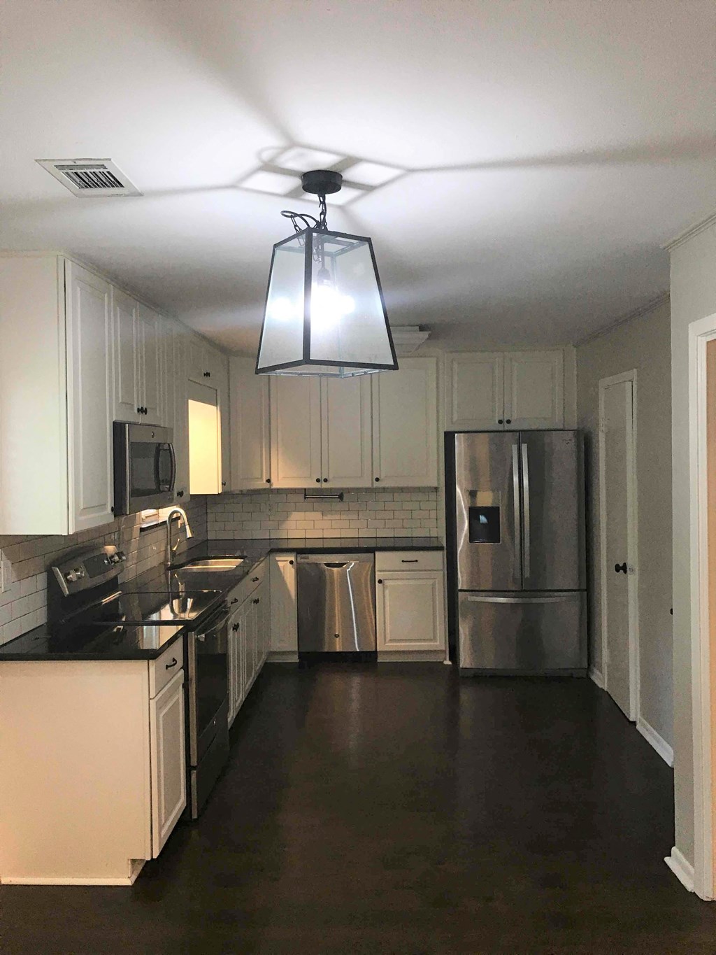A kitchen with white cabinets and a stainless steel refrigerator.