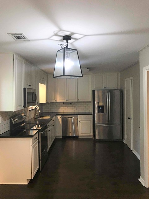 A kitchen with white cabinets and a stainless steel refrigerator.