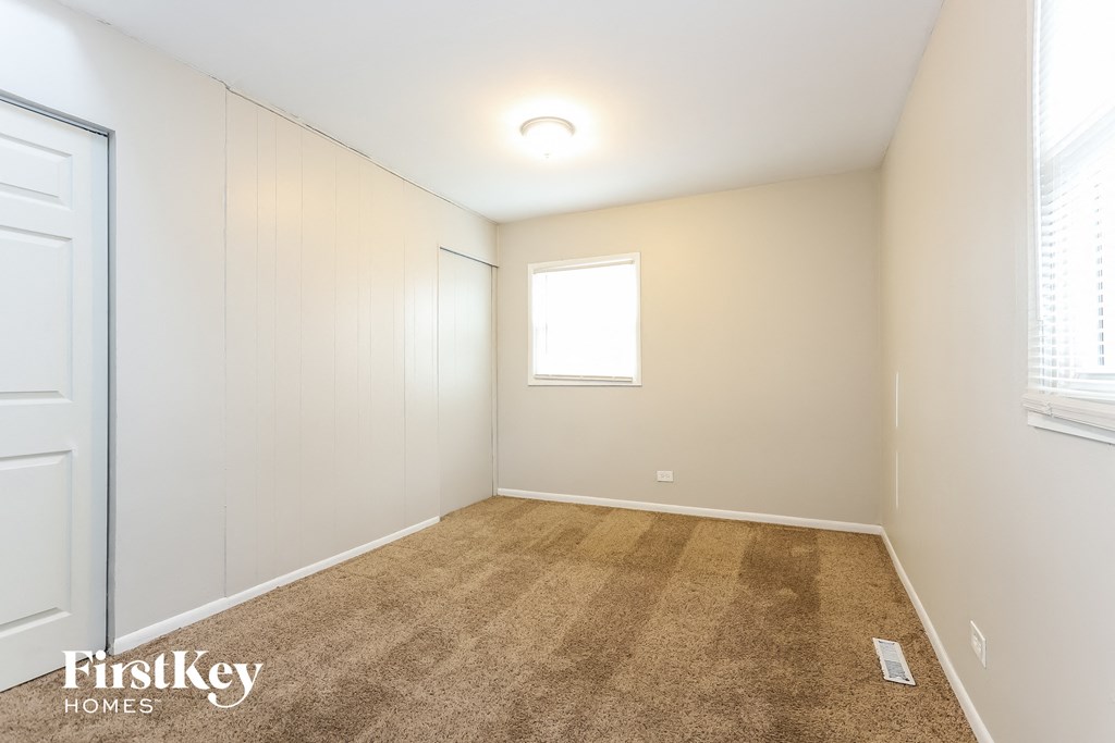 a bedroom with white walls and carpet and a window