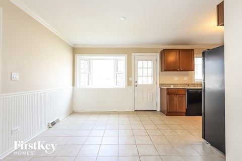 A kitchen with a black fridge, white walls, and a window.