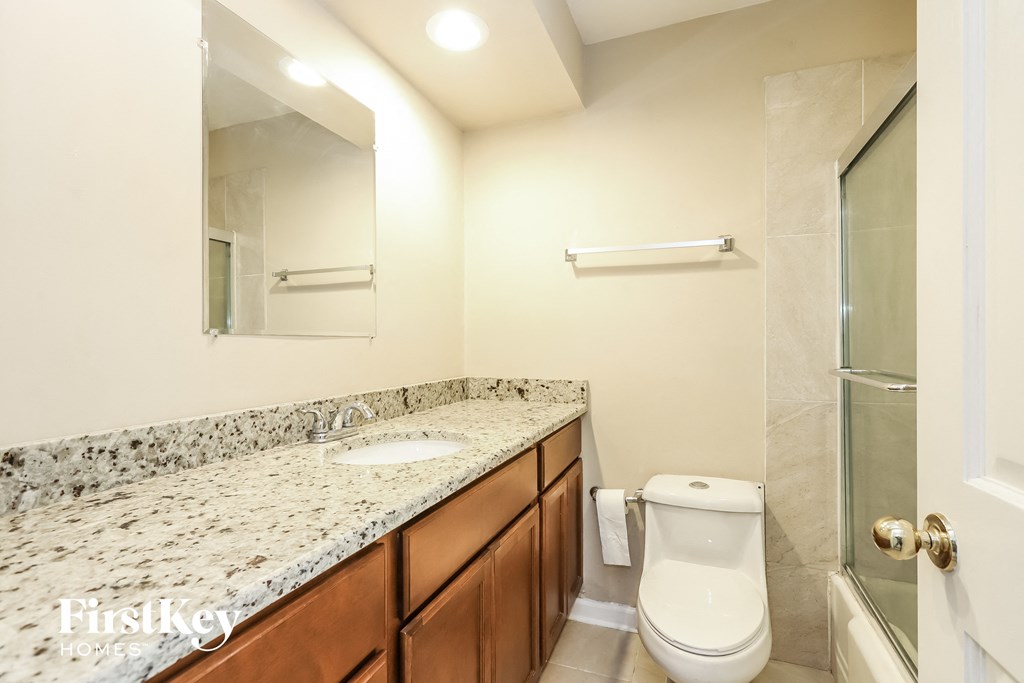 A bathroom with granite countertops and a white toilet.