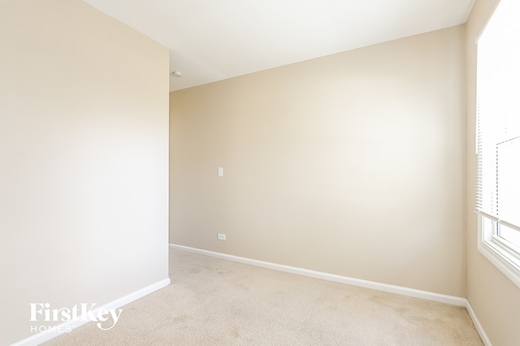 A room with a beige carpet and a window on the right side.