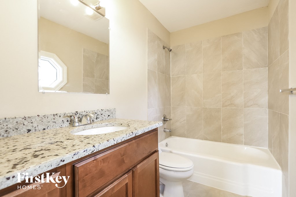 A bathroom with a tub, sink and mirror.