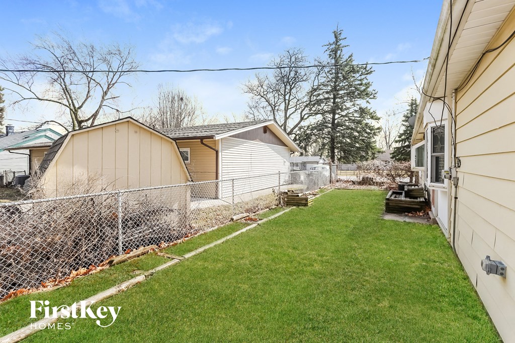 A backyard with a fence and a shed.