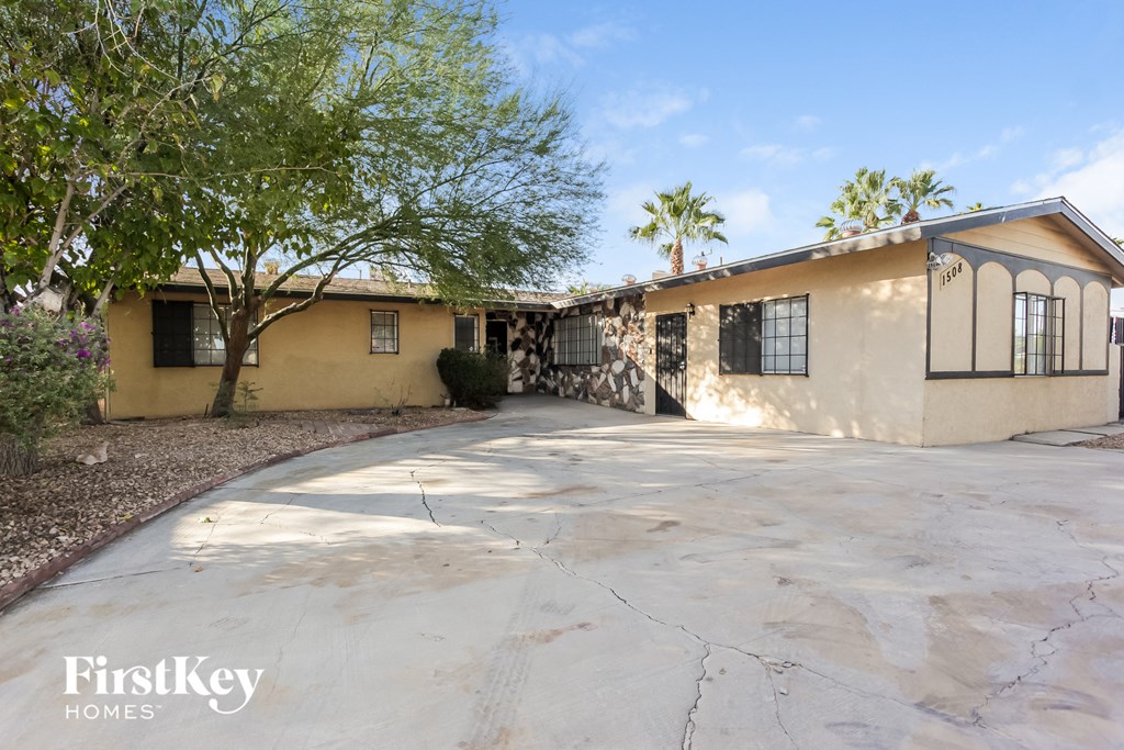 a beige house with a driveway and trees
