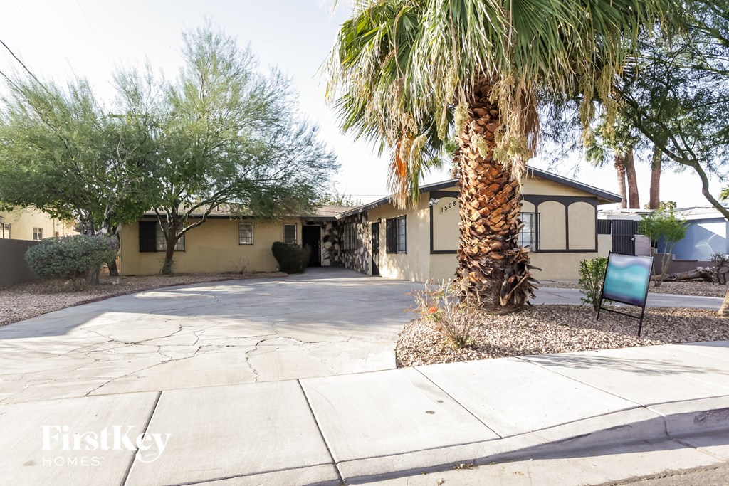 a yellow house with a palm tree and a driveway
