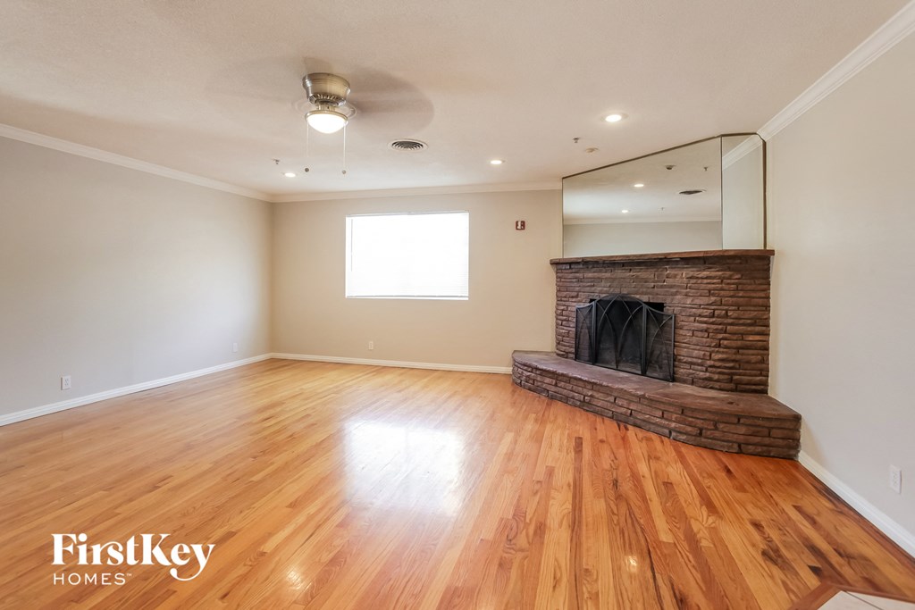 an empty living room with a fireplace and wooden floors