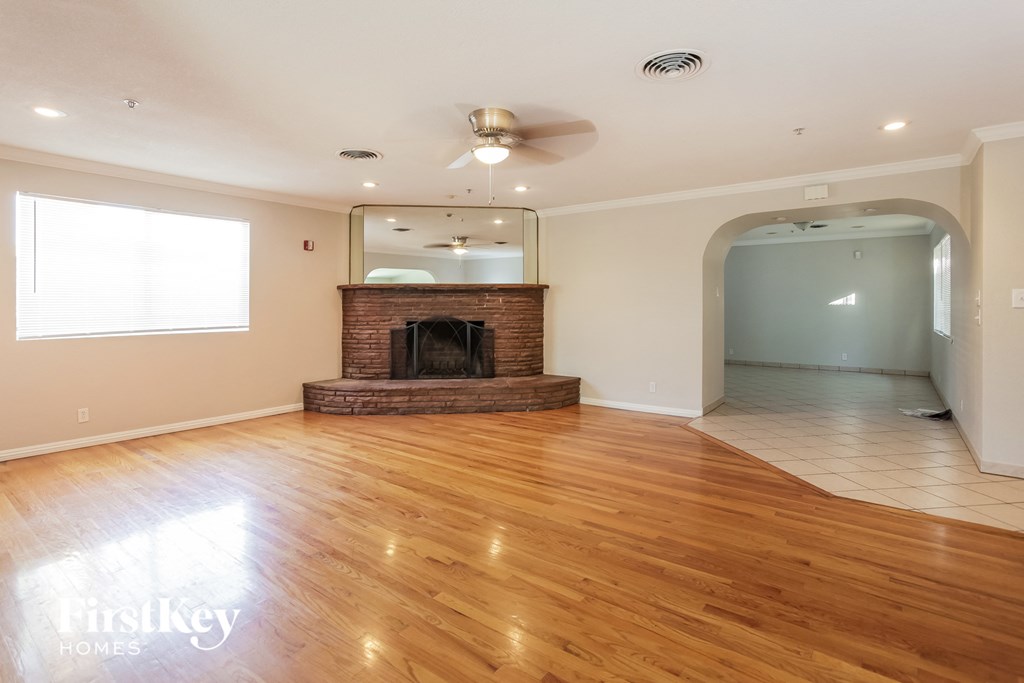 an empty living room with a fireplace and wooden floors