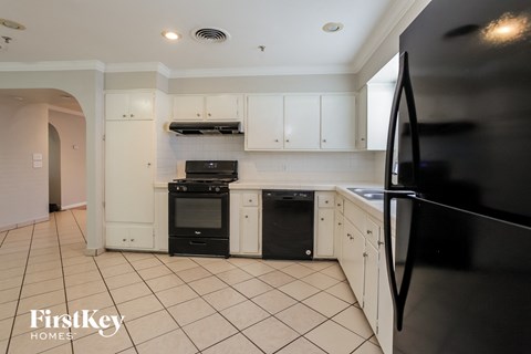 a white kitchen with black appliances and white cabinets