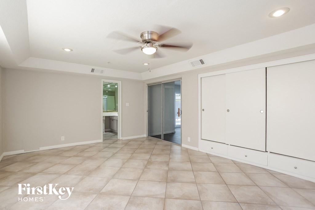 an empty living room with white cabinets and a ceiling fan