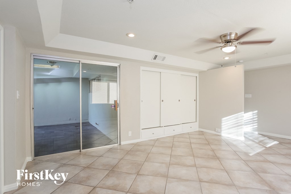 an empty living room with a ceiling fan and a closet