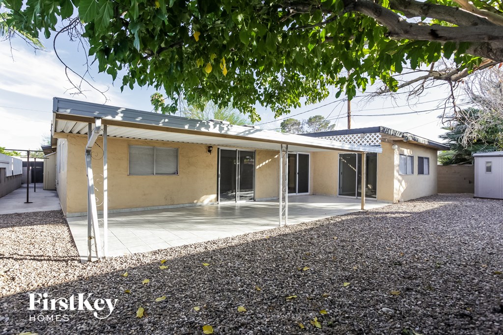 a small yellow house with a porch and a tree
