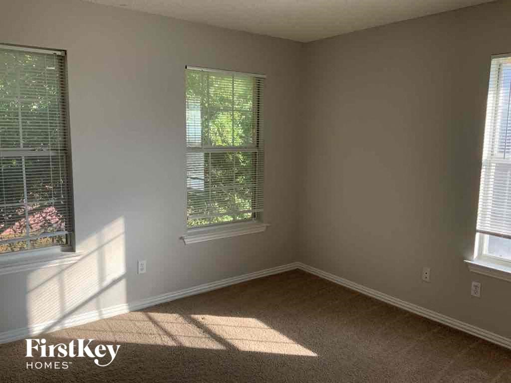 an empty room with two windows and a carpet