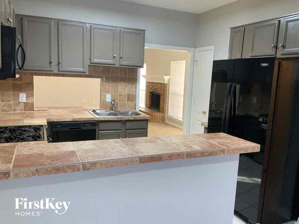 an empty kitchen with granite counter tops and black appliances