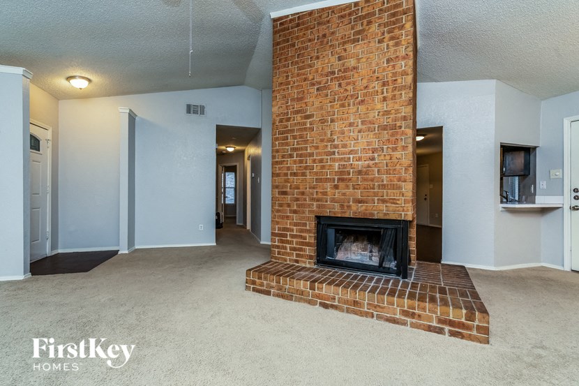 a living room with a brick fireplace and a carpeted floor