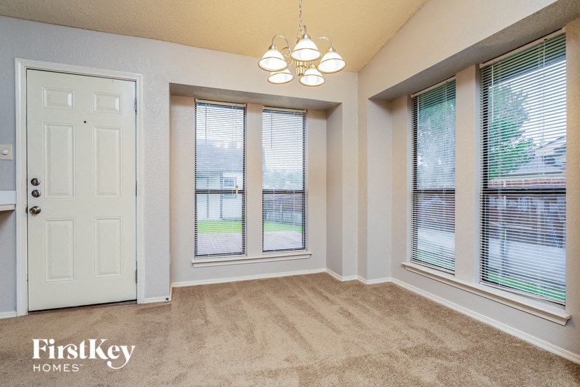 an empty living room with three windows and a white door