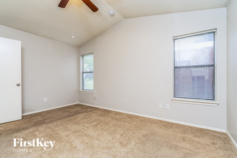 an empty living room with a window and a ceiling fan
