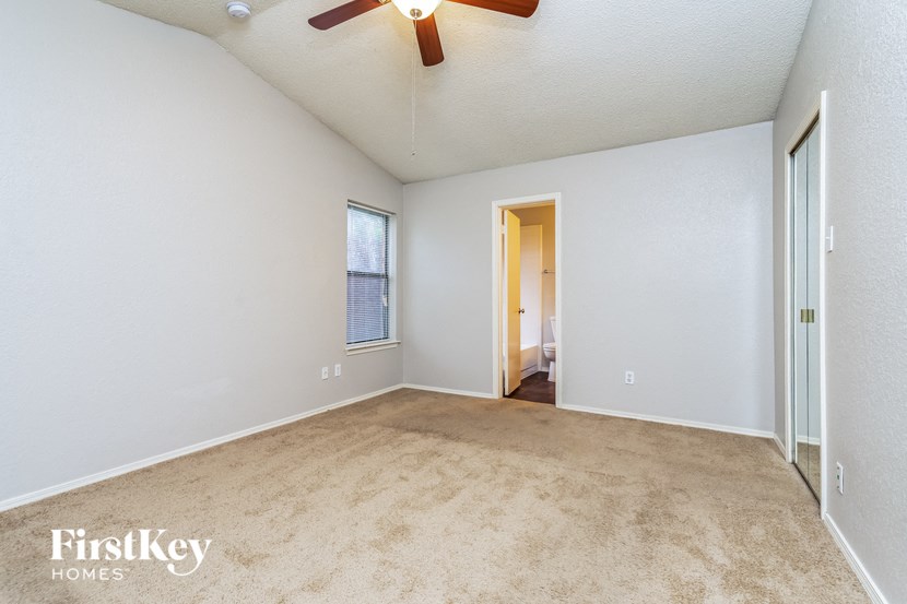 an empty living room with a ceiling fan and a window