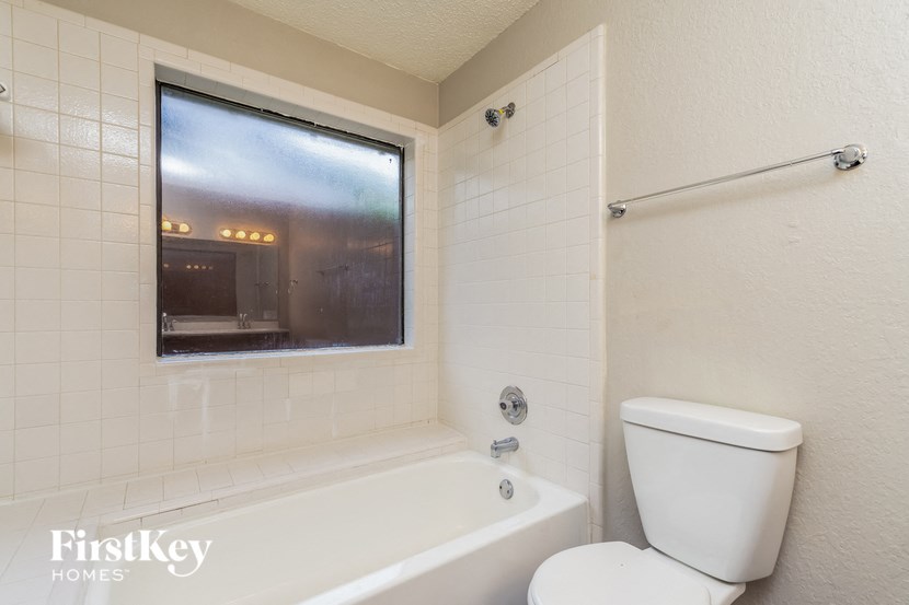 a bathroom with a toilet and a tub and a window
