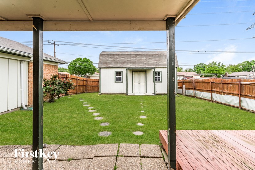 a backyard with a wooden deck and a small house