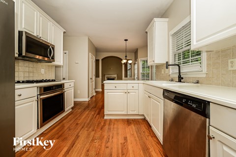 A kitchen with white cabinets and a wooden floor.