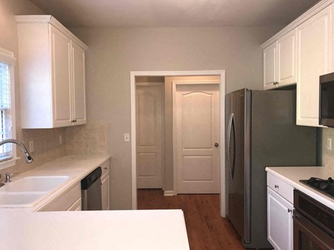A kitchen with white cabinets and a refrigerator.