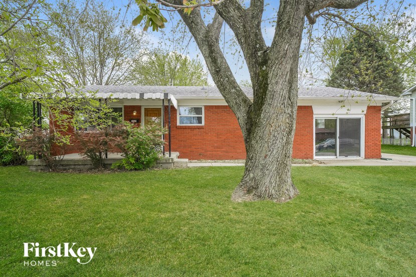 A red brick house with a tree in front of it.