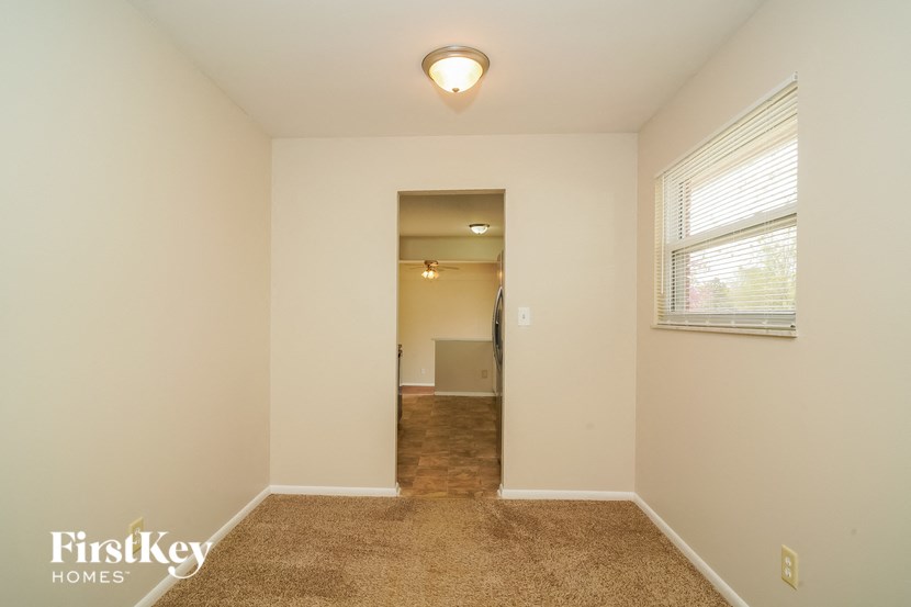 A room with a carpeted floor and a window with blinds.