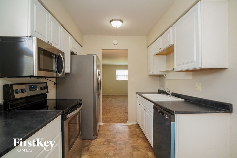 A kitchen with white cabinets and black countertops.