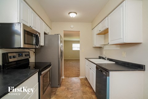 A kitchen with white cabinets and black countertops.