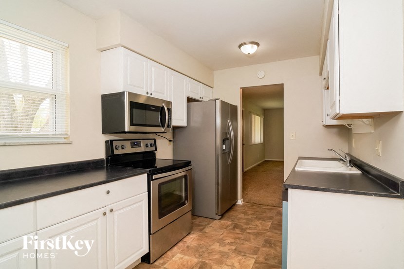 A kitchen with a black counter top and white cabinets.