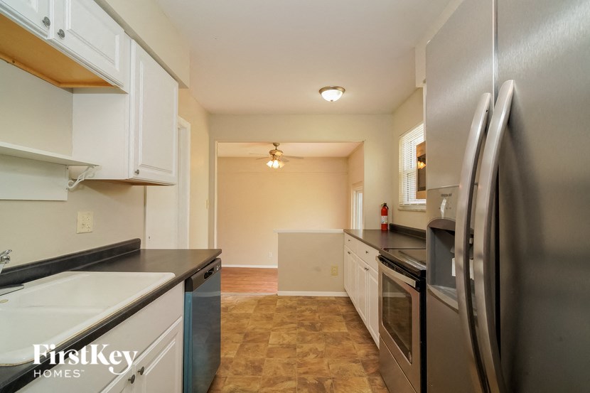 A kitchen with a refrigerator, oven, and sink.