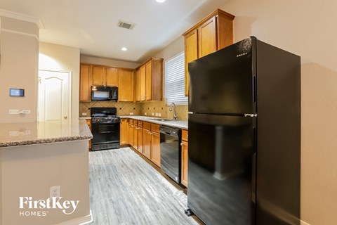 A kitchen with a black fridge and wooden cabinets.