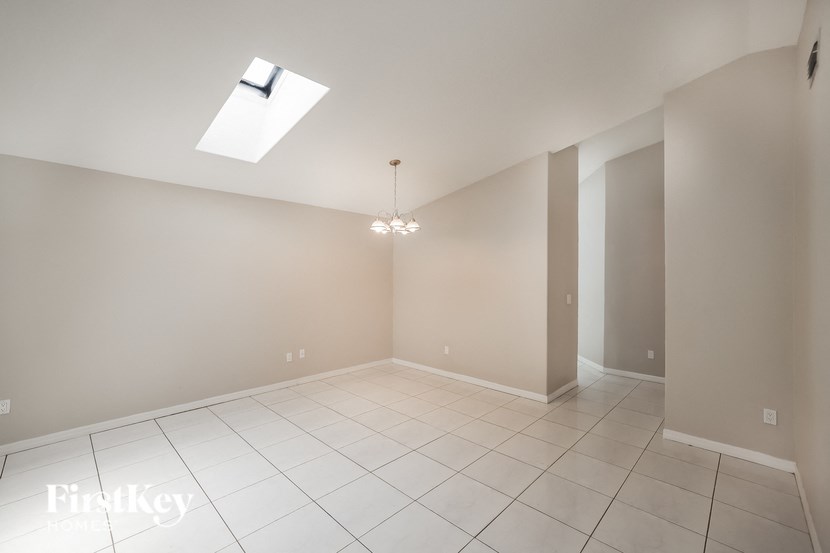 a empty living room with a ceiling light and tiled floor