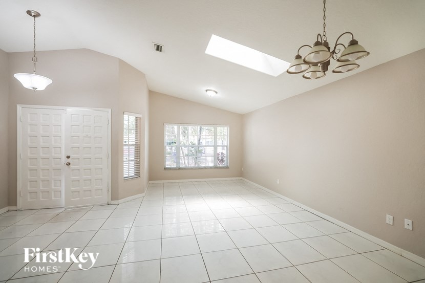 an empty living room with a white tile floor and a white door