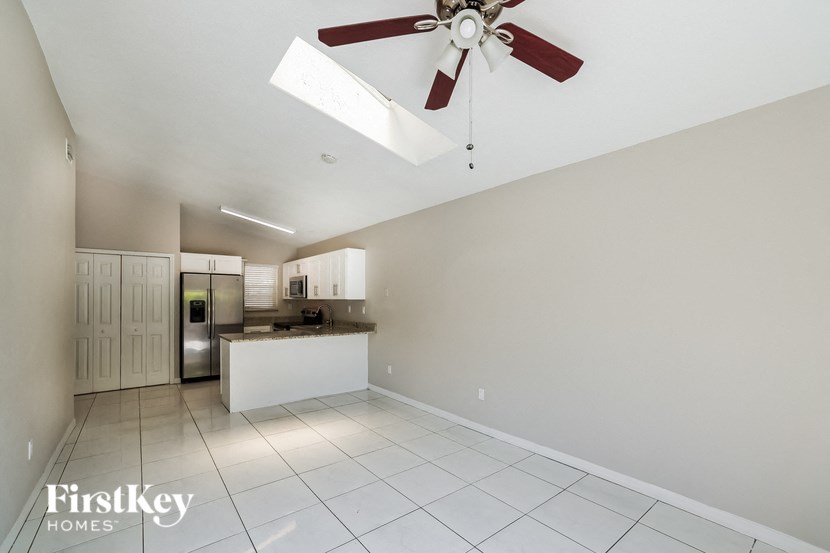 a white kitchen with a ceiling fan and white tiles